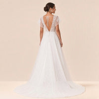 Robe de mariée en dentelle vue de dos : dos ouvert en V, cordon noué et petite traîne en tulle