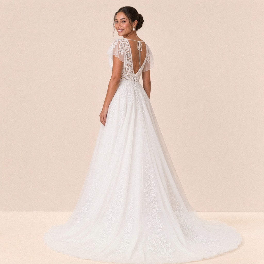 Robe de mariée en dentelle vue de trois quarts dos, petite traîne en tulle à appliques