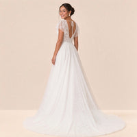 Robe de mariée en dentelle vue de trois quarts dos, petite traîne en tulle à appliques