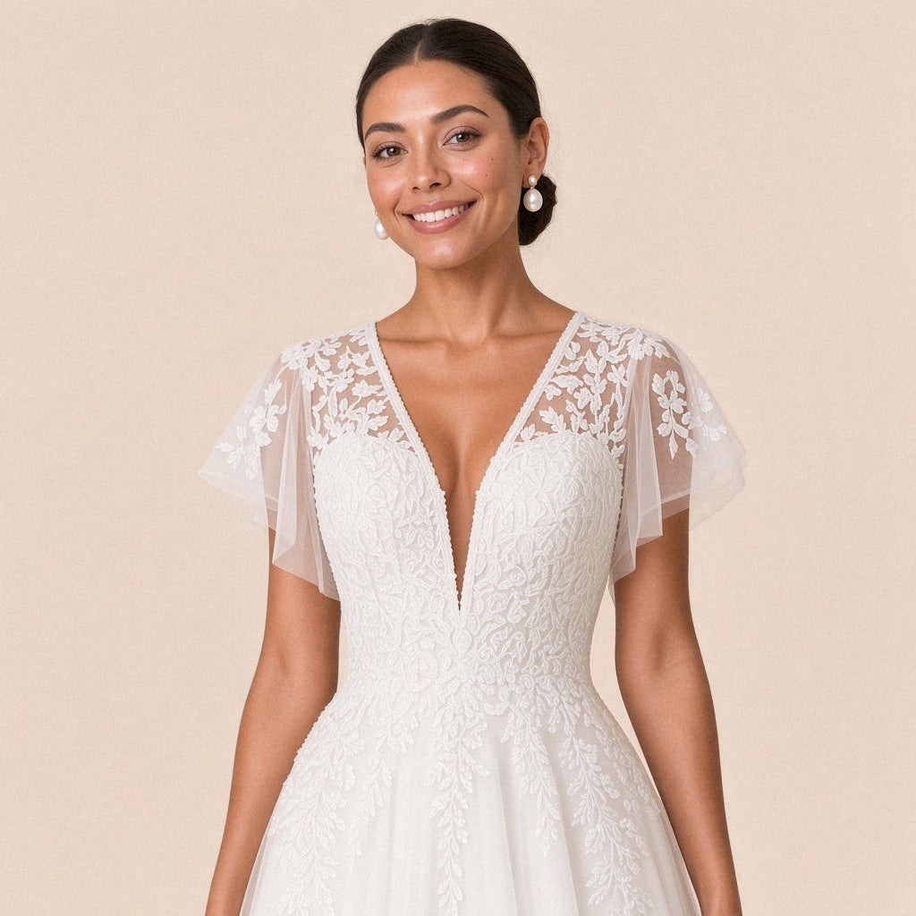 Gros plan du corsage en dentelle, décolleté en V perlé et mancherons en tulle brodé