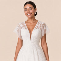 Gros plan du corsage en dentelle, décolleté en V perlé et mancherons en tulle brodé