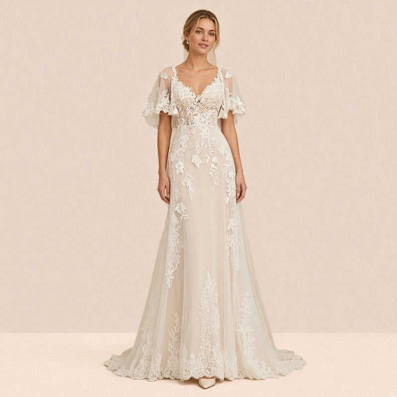Robe de mariée longue ivoire en dentelle et tulle portée de face, décolleté en V et manches cape