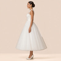 Robe de mariée en tulle de profil, col illusion et jupe volumineuse