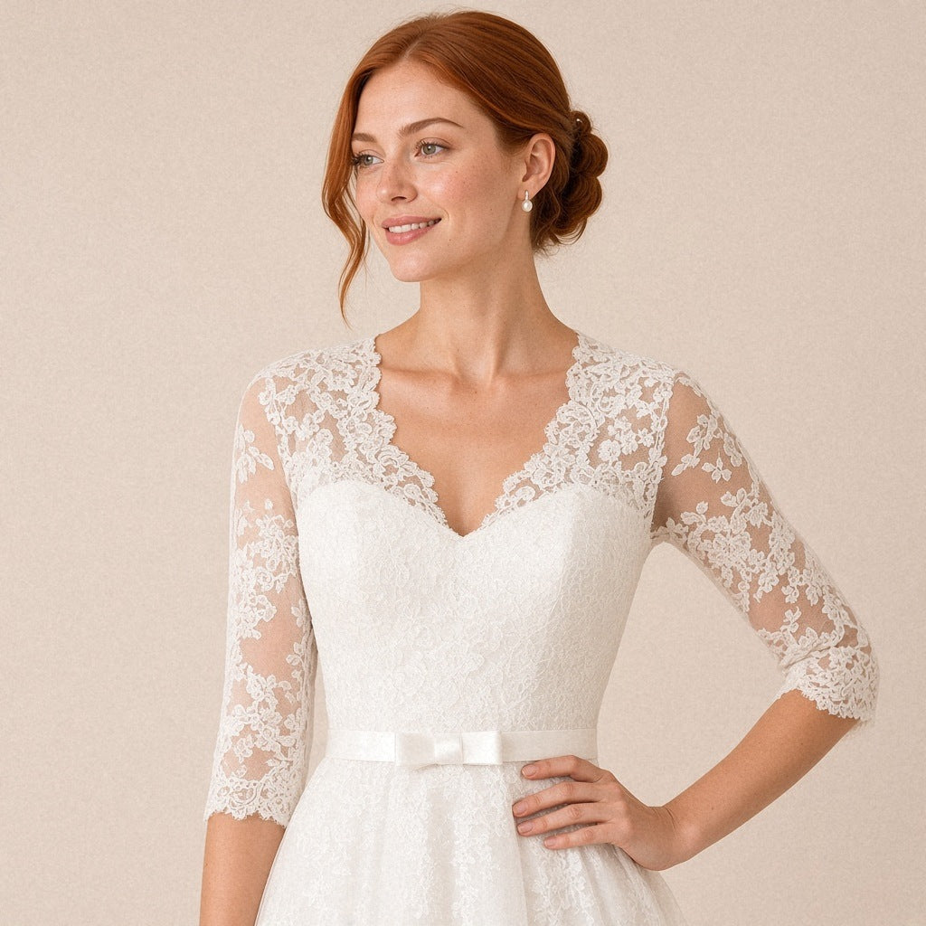 Robe de mariée mi-longue en dentelle col V et manches 3/4 – détail du buste en dentelle et de la ceinture à nœud