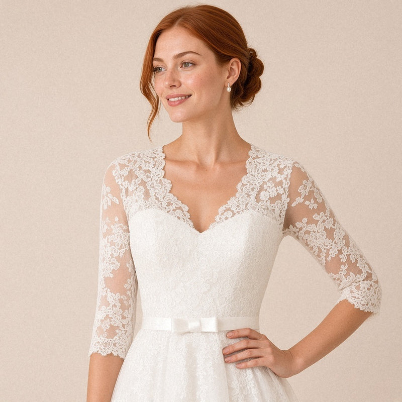 Robe de mariée mi-longue en dentelle col V et manches 3/4 – détail du buste en dentelle et de la ceinture à nœud