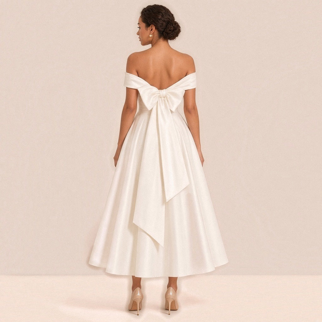 Femme de dos dans la robe de mariée mi-longue : grand nœud en satin aux longs pans