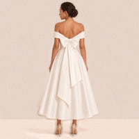 Femme de dos dans la robe de mariée mi-longue : grand nœud en satin aux longs pans