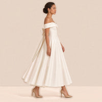 Femme de profil dans la robe de mariée mi-longue en satin, nœud au dos