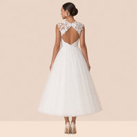 Robe de mariée blanche mi-longue – vue de dos : dos ouvert en goutte sous un empiècement de dentelle, jupe en tulle.