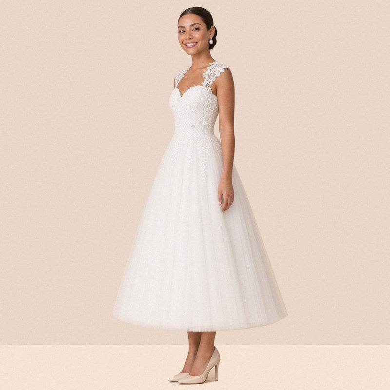 Robe de mariée blanche mi-longue en tulle à décolleté cœur et mancherons en dentelle – vue de trois quarts.