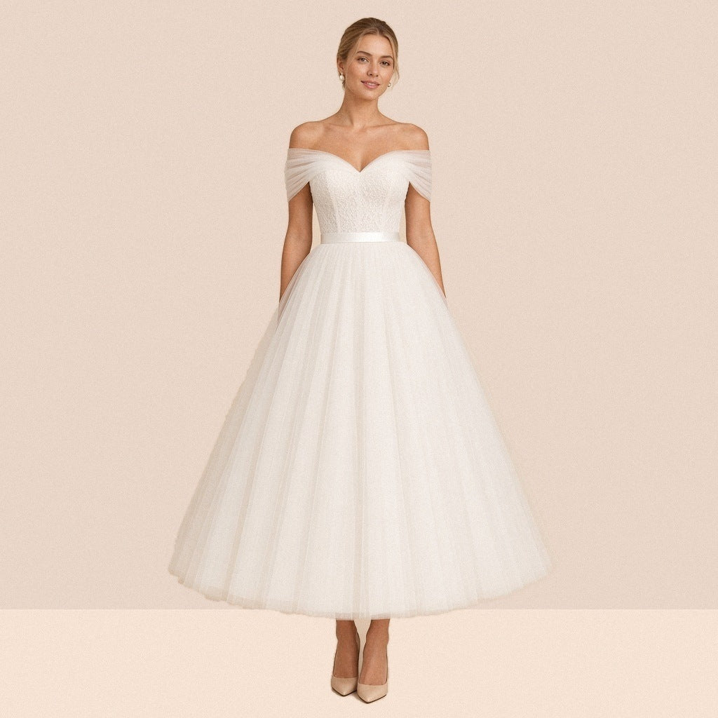 Robe de mariée ivoire mi-longue en tulle à épaules dénudées et ceinture satinée – vue de face, portée par une mannequin.