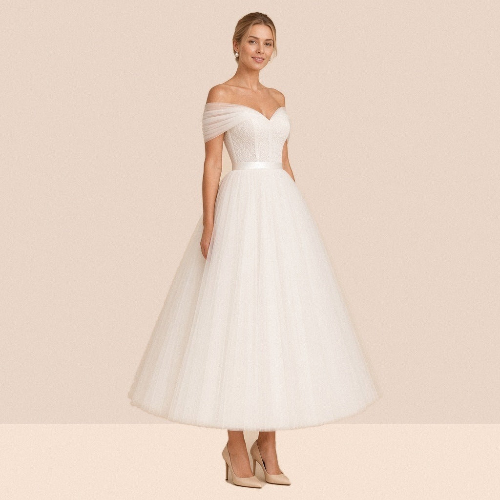 Robe de mariée ivoire mi-longue en tulle à épaules dénudées et ceinture satinée – vue de trois quarts.