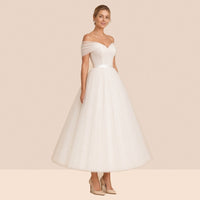 Robe de mariée ivoire mi-longue en tulle à épaules dénudées et ceinture satinée – vue de trois quarts.