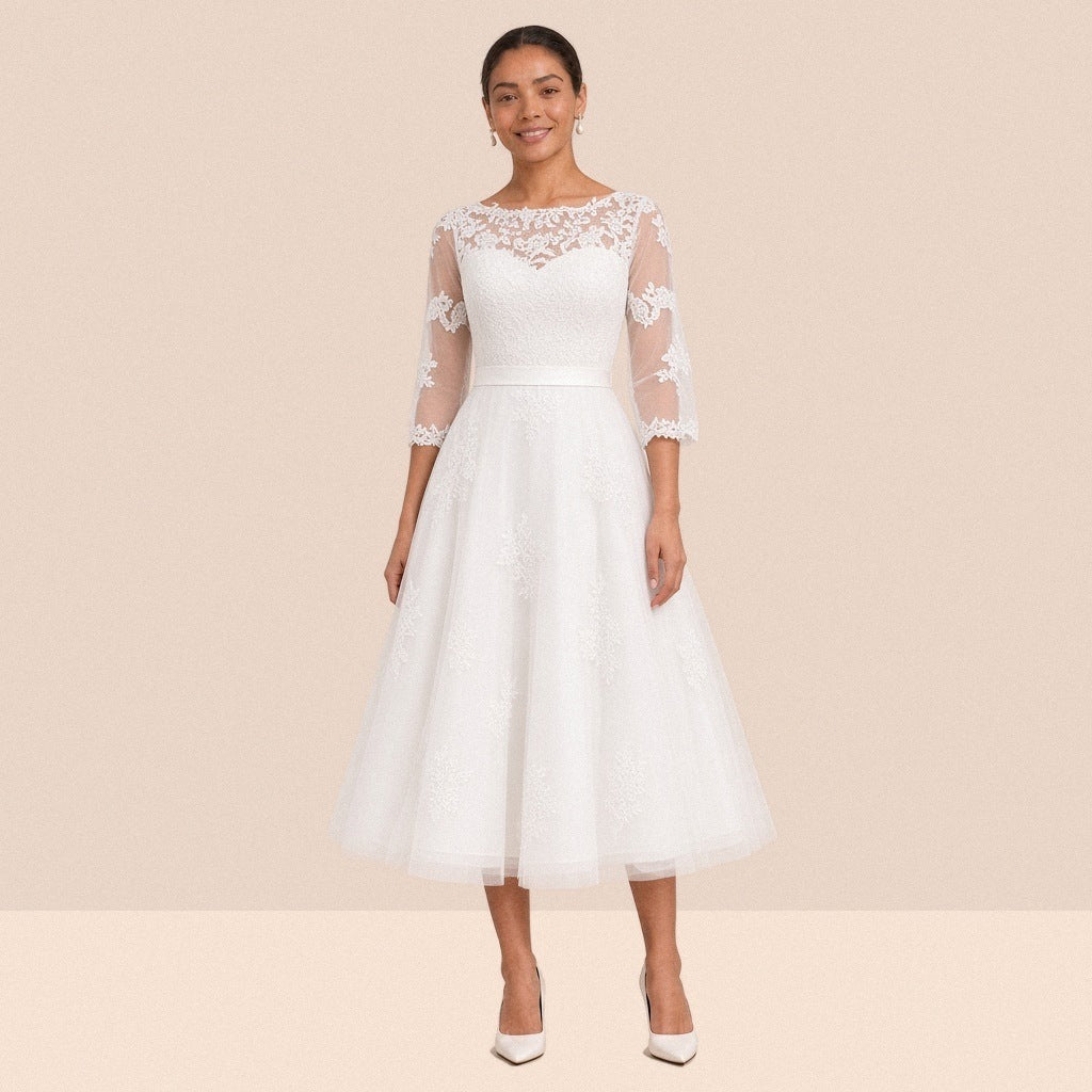 Robe de mariée blanche mi-longue en tulle portée de face, encolure illusion et manches 3/4 en dentelle