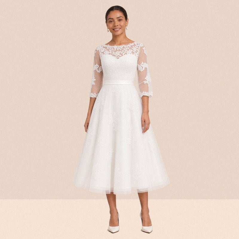 Robe de mariée blanche mi-longue en tulle portée de face, encolure illusion et manches 3/4 en dentelle