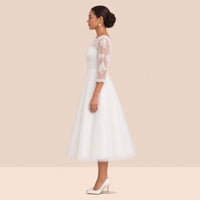 Robe de mariée en tulle de profil, manche 3/4 en dentelle et ceinture satinée