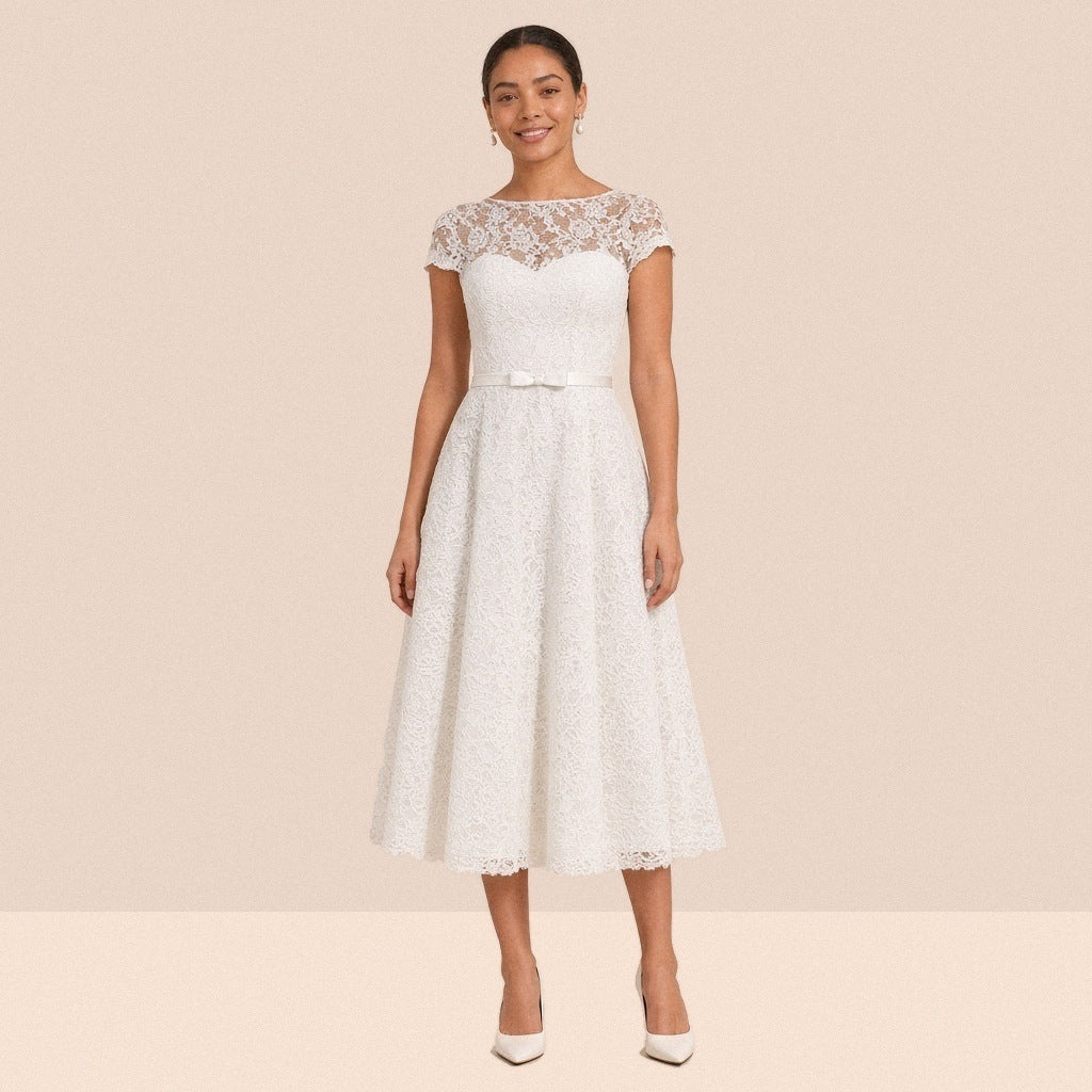 Robe de mariée midi en dentelle blanche portée de face, encolure illusion et mancherons
