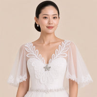 Détail du col V en guipure, de la broche strass et des manches en tulle