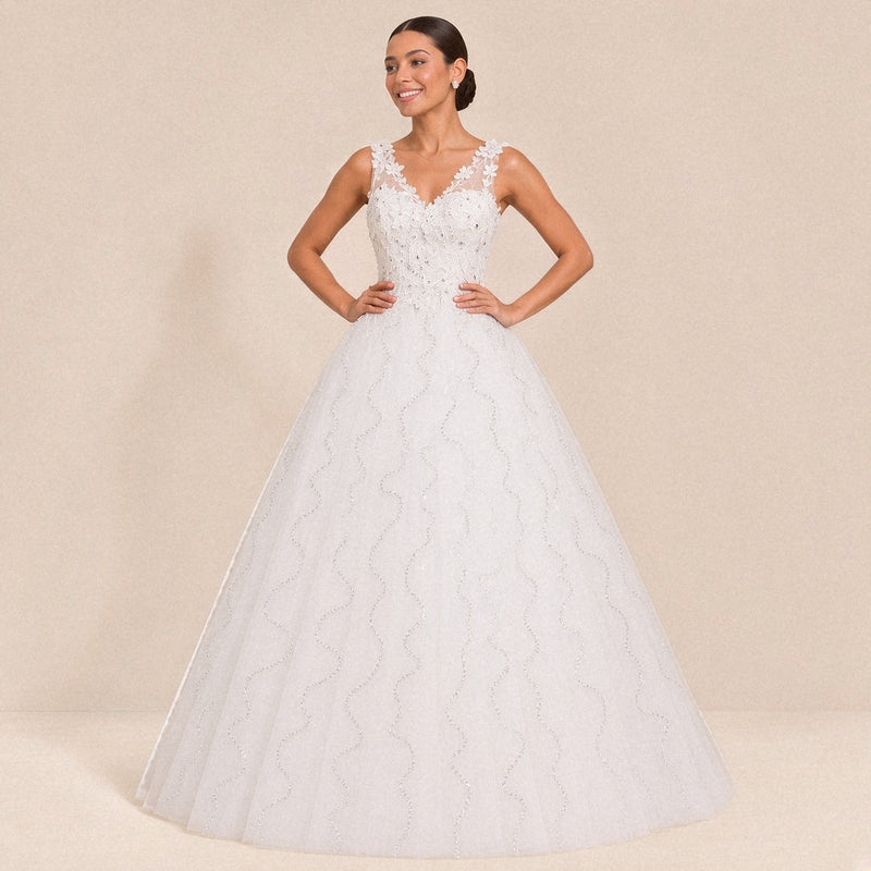 Robe de mariée princesse blanche col V à fleurs en relief, portée de face, mains à la taille