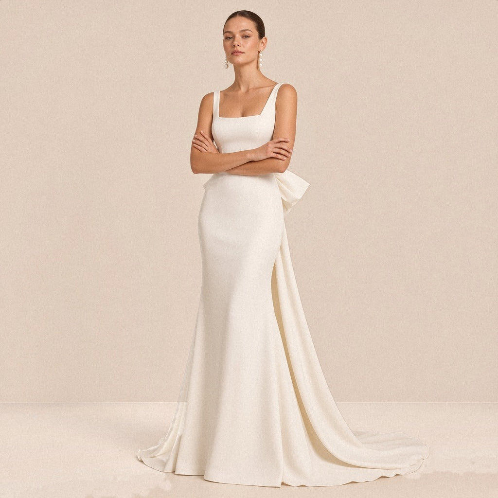 Robe de mariée sirène satinée blanche à encolure carrée, portée de face, bras croisés
