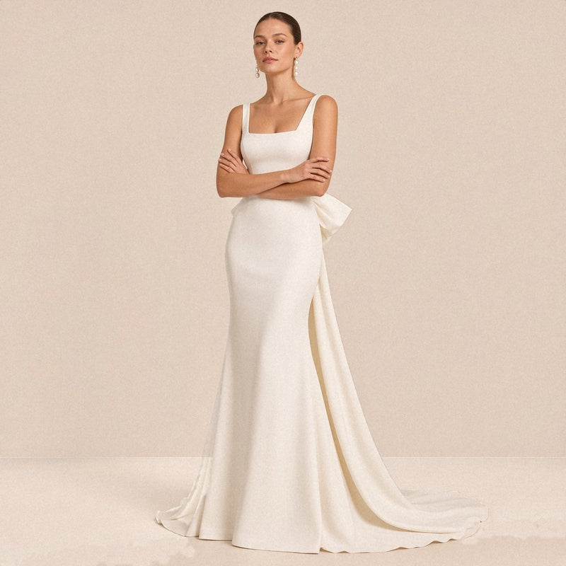 Robe de mariée sirène satinée blanche à encolure carrée, portée de face, bras croisés