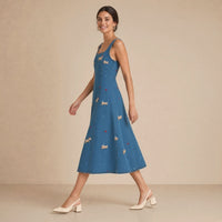 Robe midi en jean bleu denim brodée de petits teckels, portée en marchant de profil