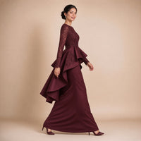 Robe de soirée longue à basque volantée, buste en dentelle brodée et manches longues, en marchant de profil, coloris bordeaux profond – SAKIWE