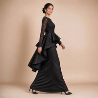 Robe de soirée longue à basque volantée, buste en dentelle brodée et manches longues, en marchant de profil, coloris noir – SAKIWE
