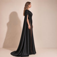 Femme de profil dans la robe de soirée noire, long pan de satin tombant de l’épaule jusqu’au sol