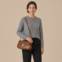 Sac baguette en similicuir caramel porté en bandoulière, vue de face, sur une femme