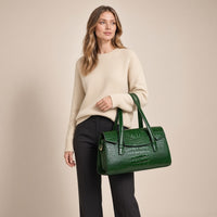 Sac Boston effet croco vert foncé, porté par une femme sur fond beige