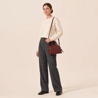 Femme portant le sac bowling demi-lune brun caramel à l’épaule avec la bandoulière amovible
