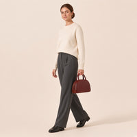 Femme marchant, sac bowling demi-lune en cuir ciré brun caramel tenu à la main par ses anses