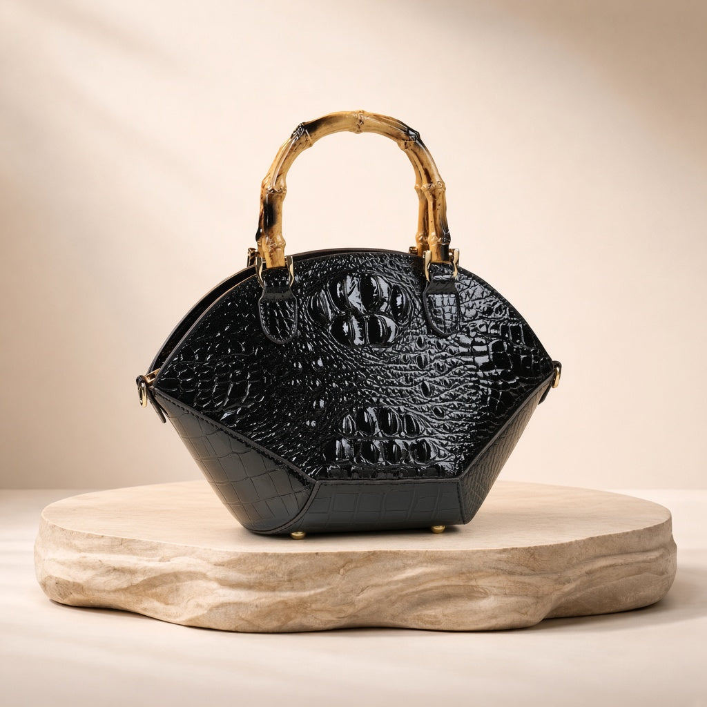 Sac coquille effet croco noir à anse bambou, posé sur un socle en pierre, vue produit