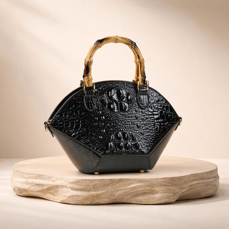 Sac coquille effet croco noir à anse bambou, posé sur un socle en pierre, vue produit