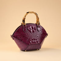 Sac coquille effet croco violet à anse bambou, vue de trois quarts sur fond beige