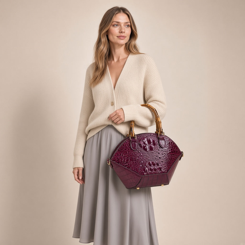Sac coquille effet croco violet à anse bambou, porté à la main par une femme sur fond beige