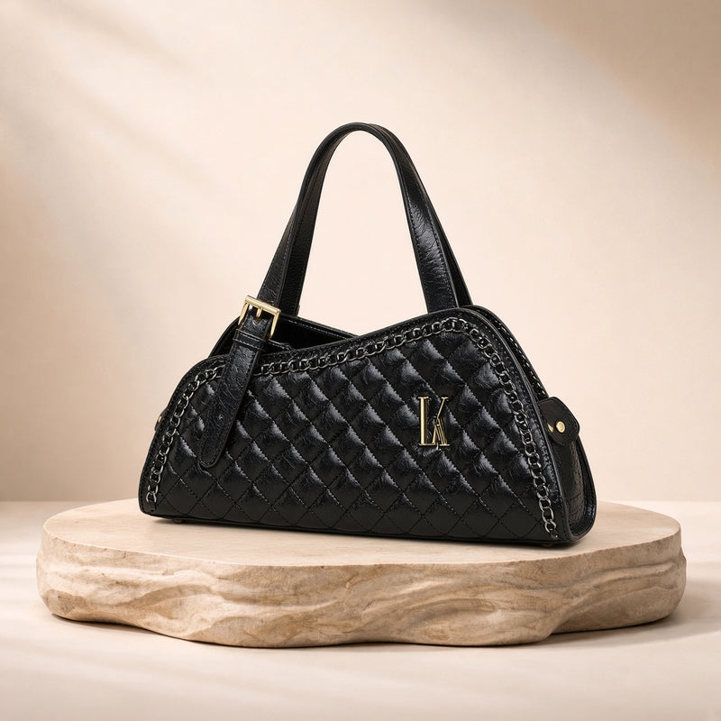 Sac porté épaule en cuir matelassé à chaîne SAKIWE noir, posé sur un socle en pierre