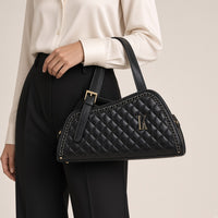 Sac porté épaule en cuir matelassé noir, détail de la boucle dorée tenu à la main