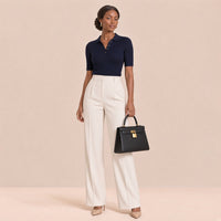 Femme en polo marine et pantalon crème tenant le sac en cuir grainé SAKIWE noir à la main