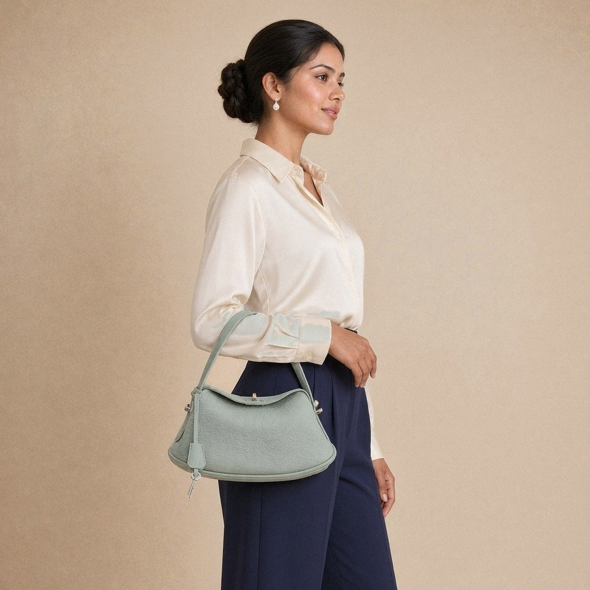 Sac oreiller en cuir grainé SAKIWE vert sauge porté à l’épaule, vue de profil