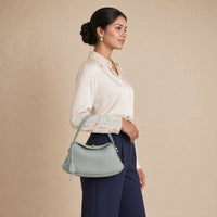 Sac oreiller en cuir grainé SAKIWE vert sauge porté à l’épaule, vue de profil