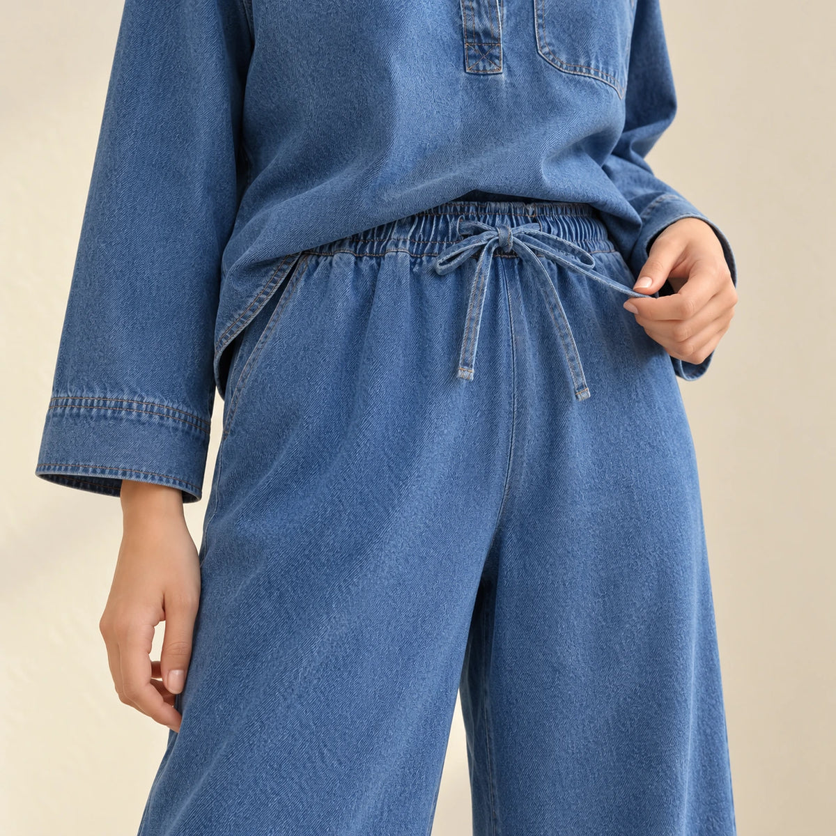 Détail de la taille élastique du pantalon en jean bleu avec lien à nouer.