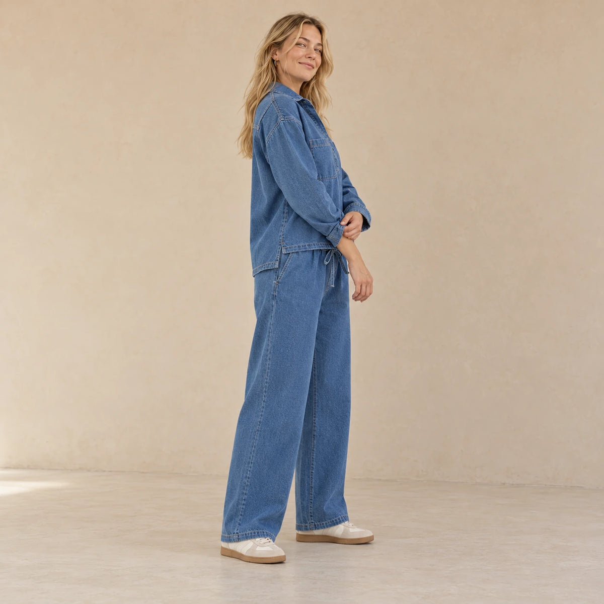 Vue de profil de l’ensemble en jean bleu porté, montrant le haut ample et la coupe large du pantalon.