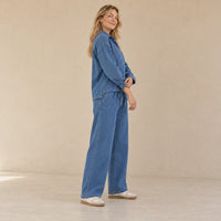 Vue de profil de l’ensemble en jean bleu porté, montrant le haut ample et la coupe large du pantalon.