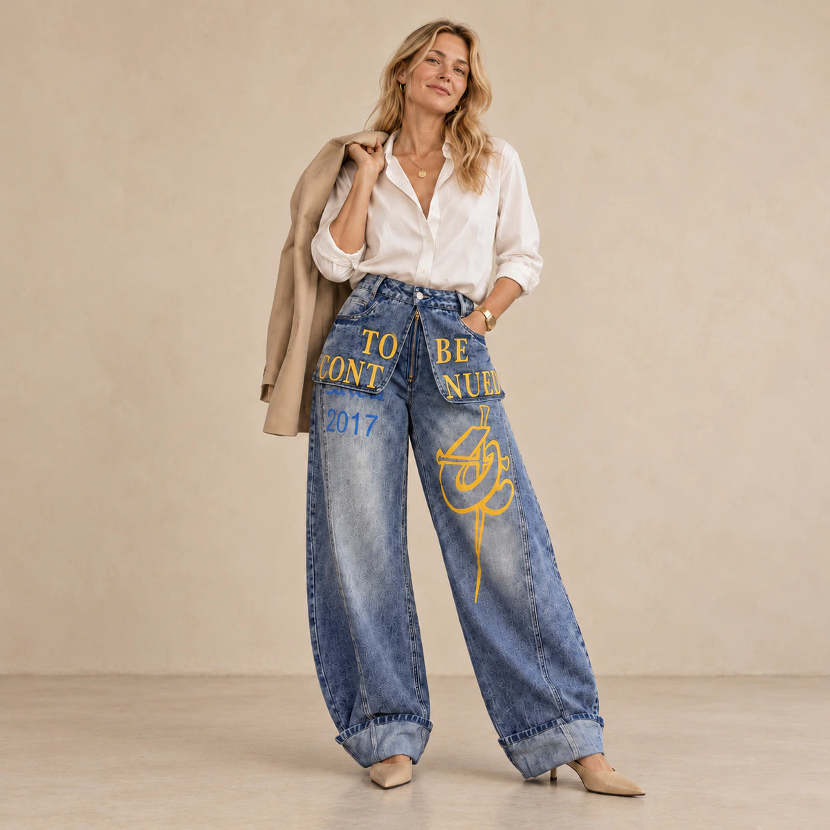 Jean large bleu SAKIWE porté avec une veste beige sur l’épaule.