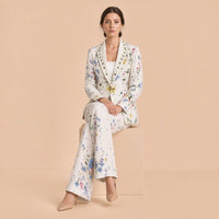 Tailleur blanc fleuri porté assis, pantalon évasé