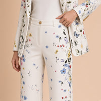 Détail du pantalon taille haute à bouton doré et des boutons dorés au poignet