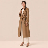 Trench long en cuir et microfibre SAKIWE camel contrasté porté de trois quarts, main au revers