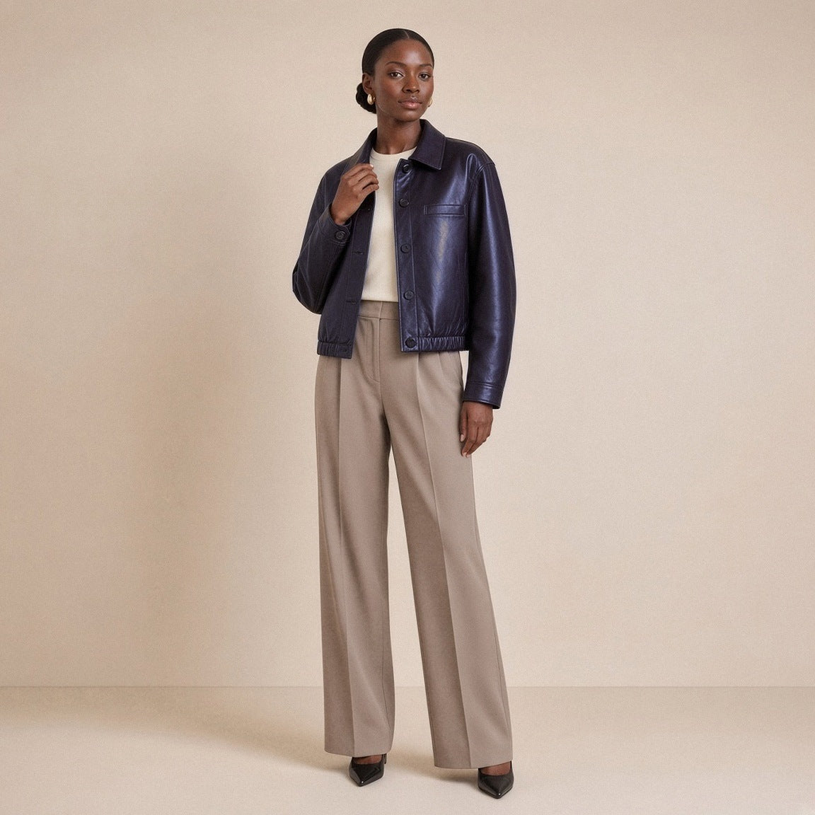 Veste ample en cuir de mouton noir aubergine à col chemise portée, vue de trois quarts, main au col